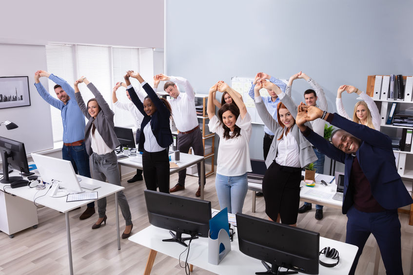 Group Of Smiling Multi-ethnic Businesspeople Doing Stretching Exercise At Workplace
